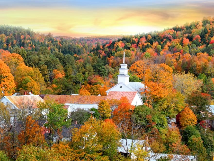A white church steeple among autumn trees